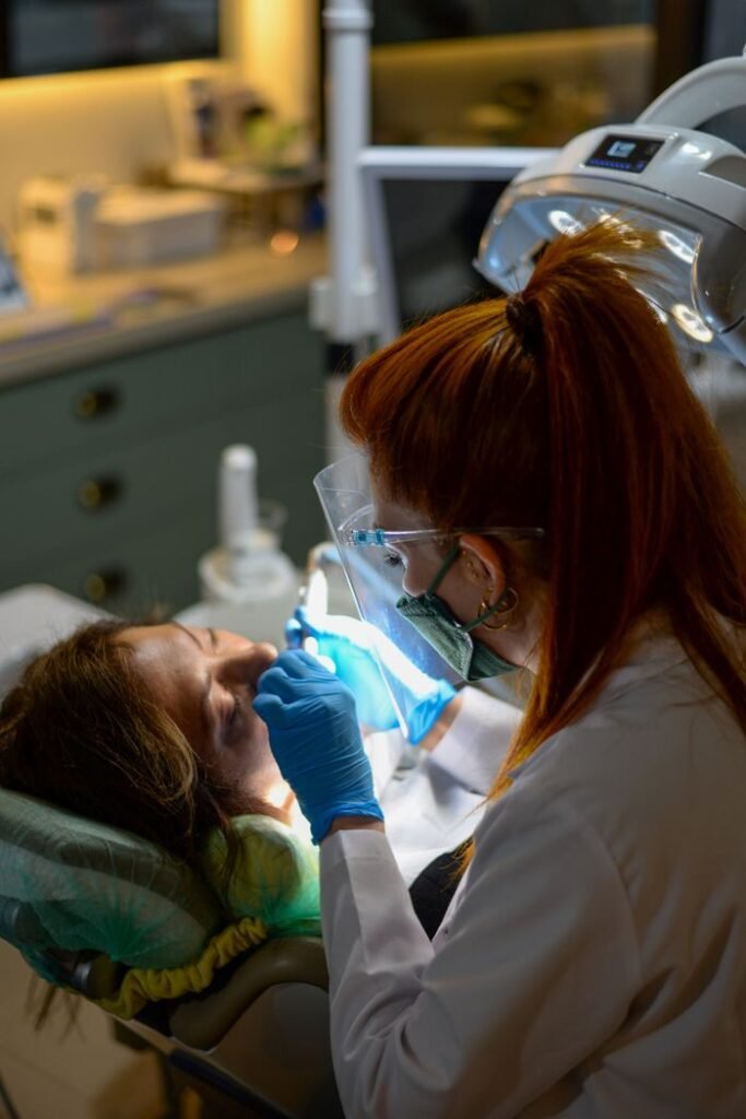pexels-photo-19976568-19976568 A dentist performing a dental procedure on a patient under bright clinic lights.